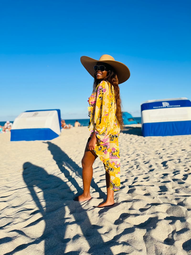 Mima in a wide-brimmed hat on a sunny beach