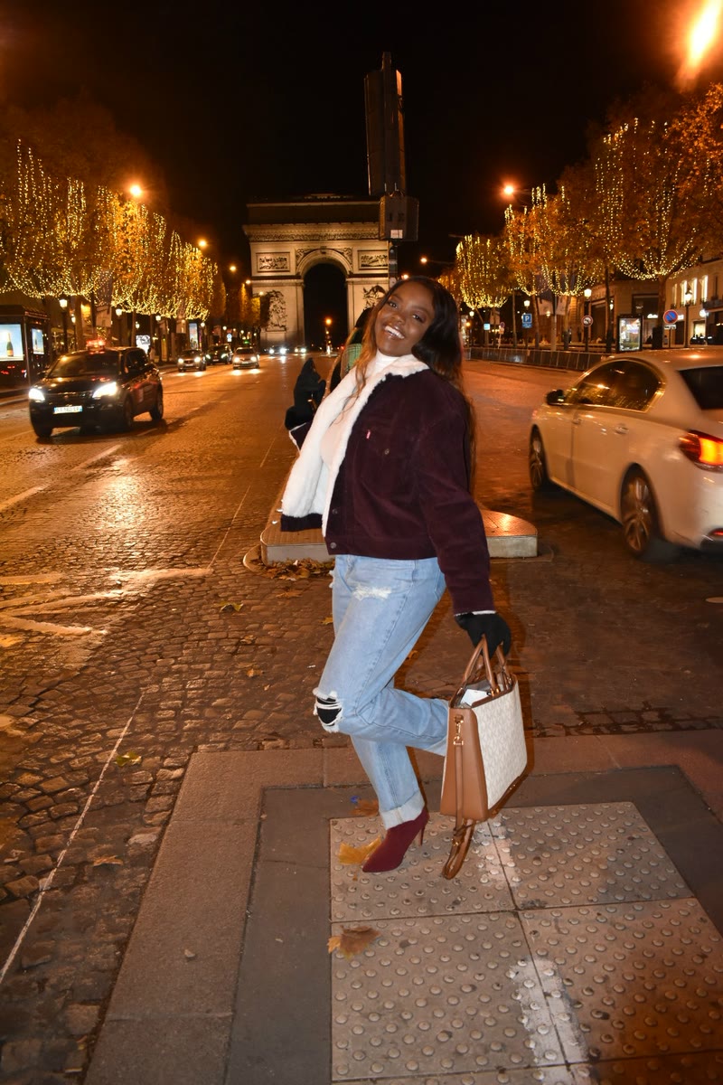 Mima on the Champs-Élysées at night, with the Arc de Triomphe behind her