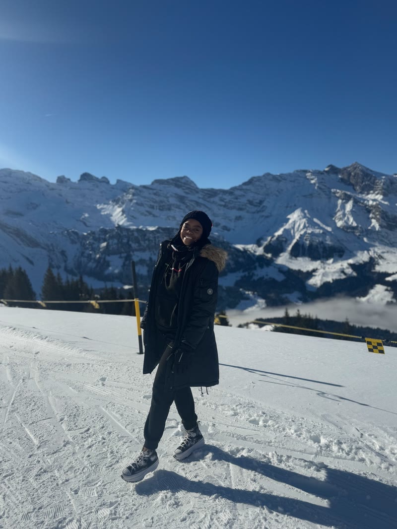 Mima on a snowy slope with mountains behind her